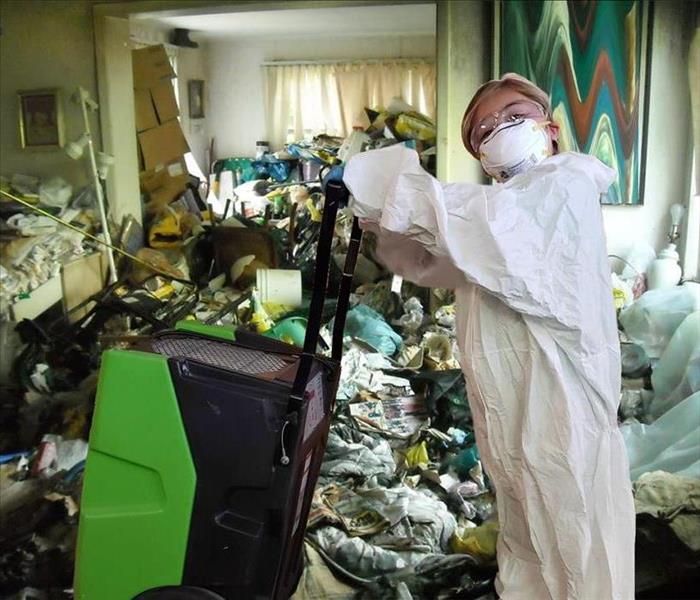 Girl in white hazmat suit in very cluttered room