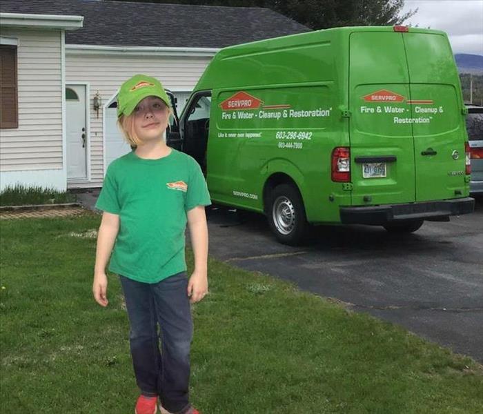 girl standing in front of a house and next to a SERVPRO van