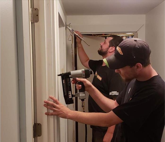 Two men putting up drywall