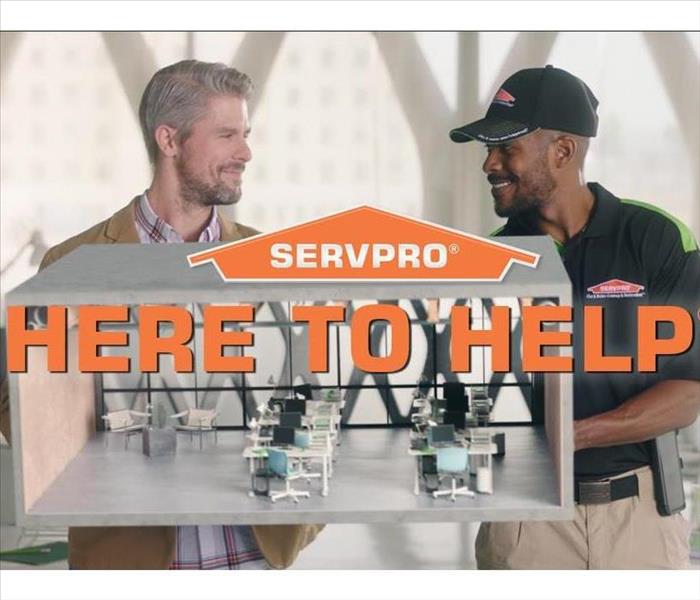  servpro employee and client standing behind servpro logo and here to help