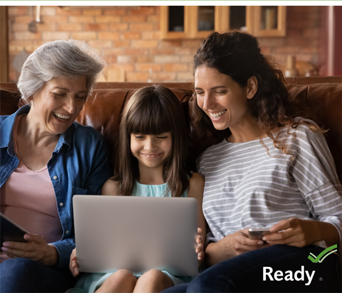 Picture of two woman and a young girl looking at a laptop with the word ready in the bottom right corner